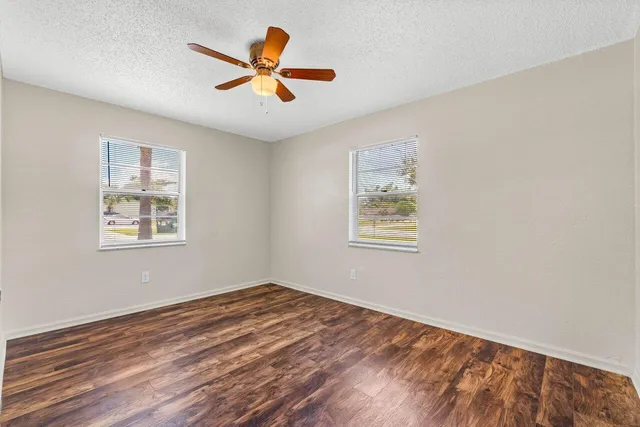 a view of empty room with wooden floor and ceiling fan