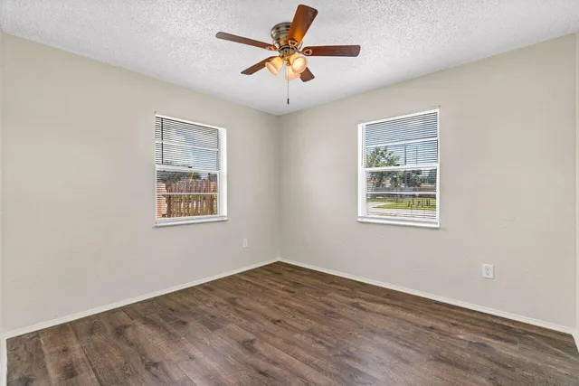 a view of a livingroom with a window a ceiling fan and wooden floor