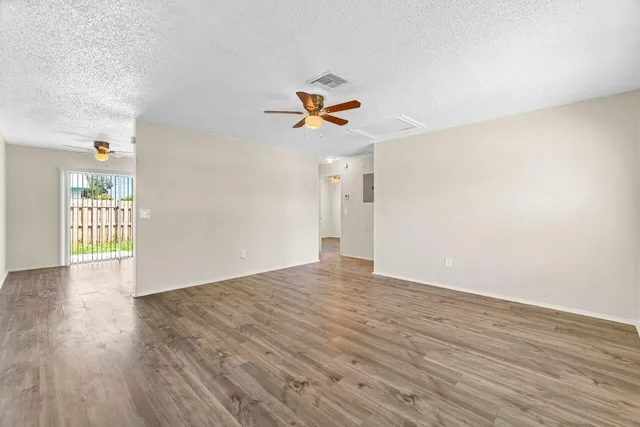 a view of an empty room with window and wooden floor