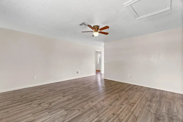 a view of a room with wooden floor and a ceiling fan
