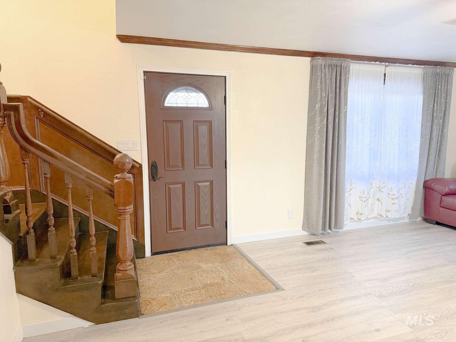 1158 South Powerline Road Nampa, ID 83686 - Photo 12 of 46 Foyer featuring a hardwood staircase with carved balusters and a paneled entry door with an arched leaded glass insert