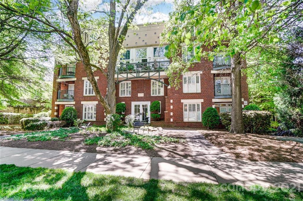 a view of a brick building next to a yard with large trees