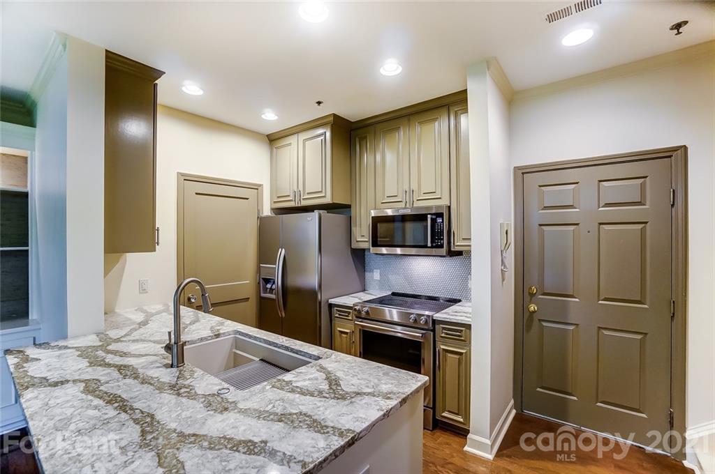 416 Queens Road Charlotte, NC 28207 - Photo 2 of 25 a kitchen with kitchen island granite countertop a refrigerator stove and oven