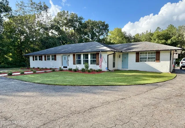 a front view of a house with a big yard and potted plants