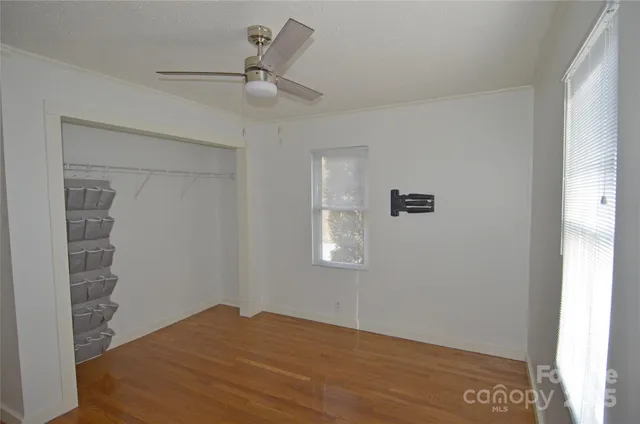a view of empty room with wooden floor and fan