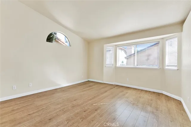 an empty room with wooden floor cabinet and windows