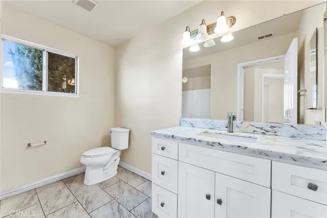 a bathroom with a granite countertop toilet sink and mirror