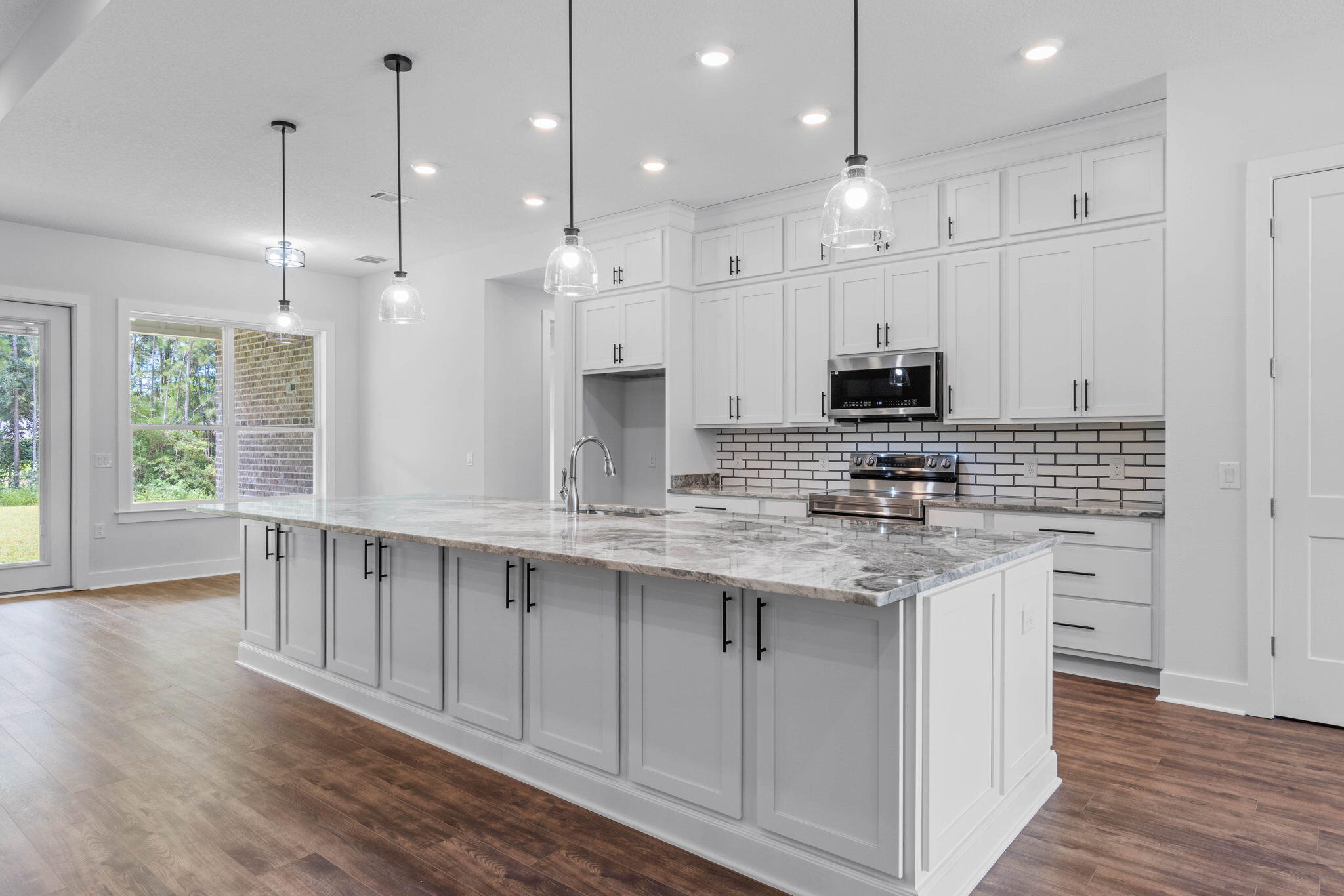 6949 Snug Waters Road Navarre, FL 32566 - Photo 3 of 51 a kitchen with kitchen island granite countertop a sink a center island stainless steel appliances and a window