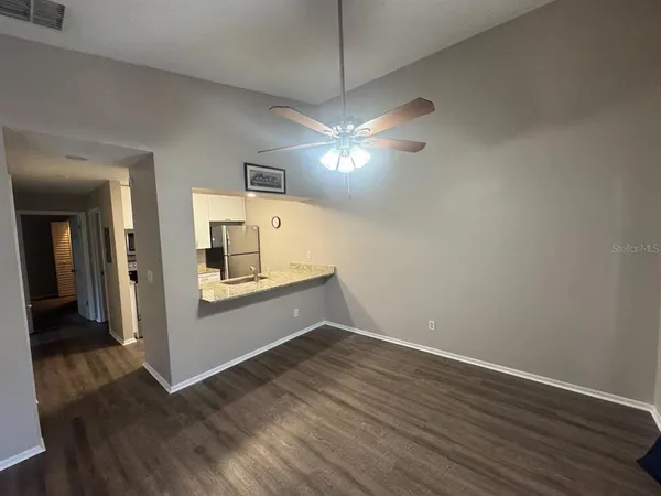 an empty room with wooden floor and ceiling fan