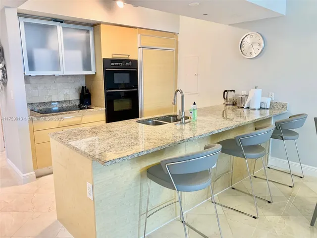 a kitchen with granite countertop a sink cabinets and stainless steel appliances