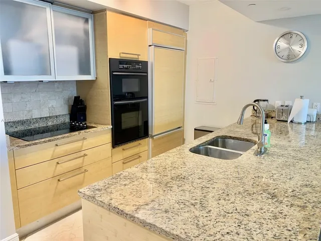 a kitchen with granite countertop a sink a stove and cabinets