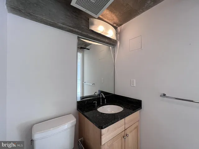 a bathroom with a granite countertop sink and a toilet