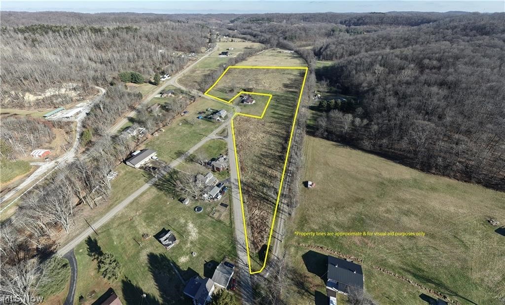 Aerial view of property and surrounding area featuring a forest and property parcel outlined