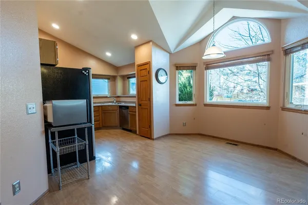 an empty room with windows wooden table and chairs