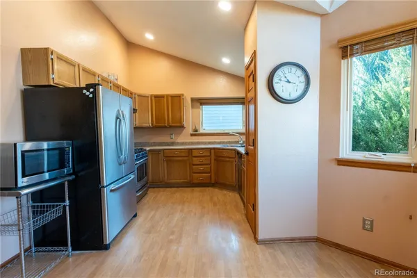 a kitchen with stainless steel appliances granite countertop a refrigerator a stove and a wooden floors
