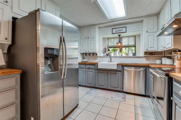 a kitchen with stainless steel appliances granite countertop a refrigerator a stove and a sink