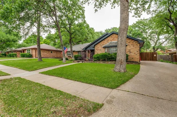 a view of a house with a yard and large trees