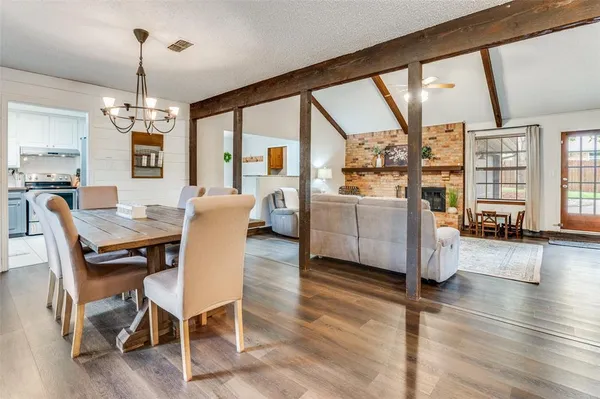 a dining room with wooden floor a chandelier a glass table and chairs