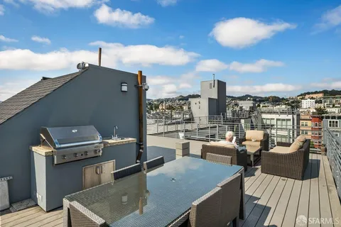 a view of a rooftop deck with couch and chairs