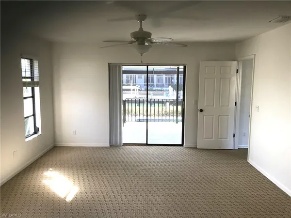 an empty room with windows and fan