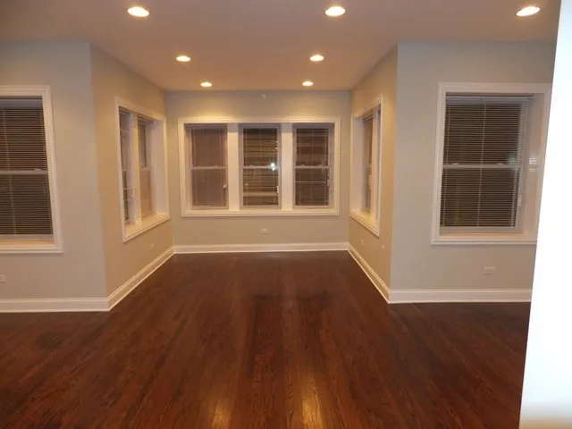 a view of an empty room with wooden floor and windows