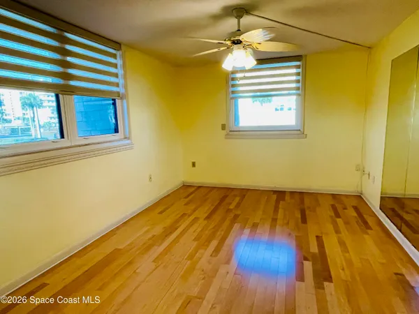 a view of a room with wooden floor and ceiling fan