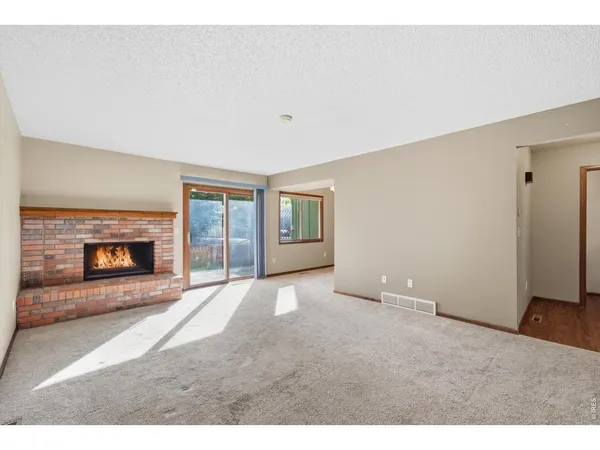 a view of an empty room with a fireplace and a window