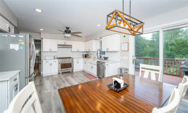 a kitchen with stainless steel appliances granite countertop a refrigerator a stove a sink dishwasher and white cabinets with wooden floor