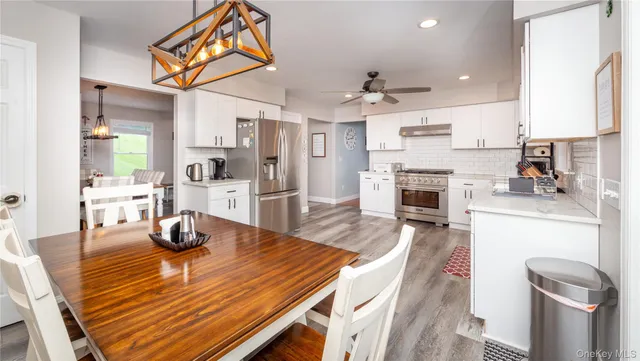 a dining room with wooden floor a chandelier a wooden table and chairs