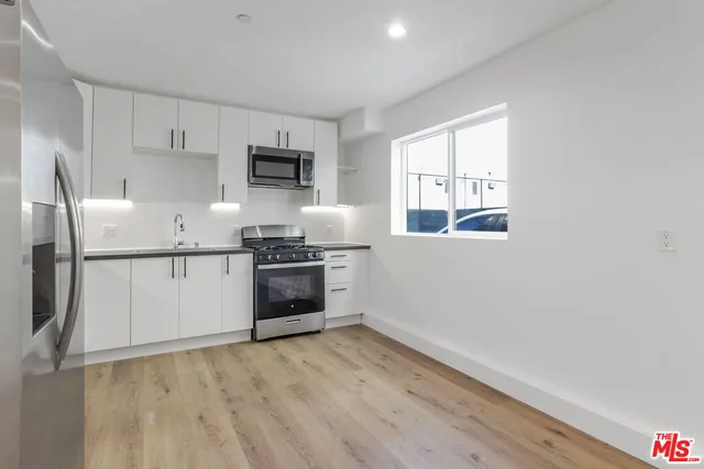 a kitchen with granite countertop white cabinets and stainless steel appliances