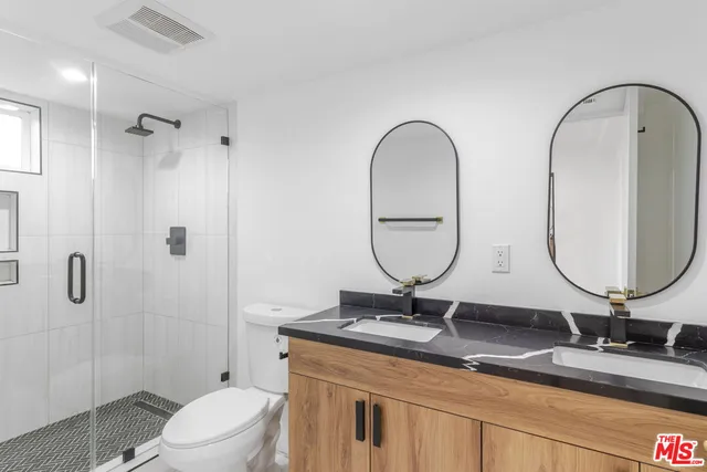 a bathroom with 2 sink toilet and a mirror