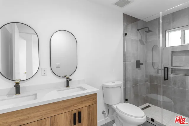 a bathroom with a double vanity sink toilet and a mirror
