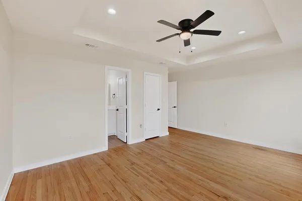 an empty room with ceiling fan and wooden floor