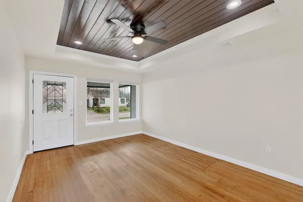 a view of an empty room with a window and wooden floor