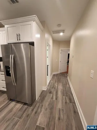 a view of a refrigerator in kitchen and an empty room