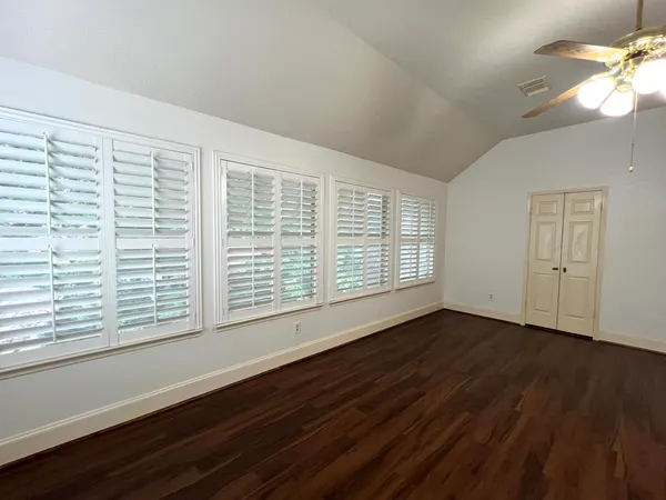 a view of an empty room with wooden floor and a window