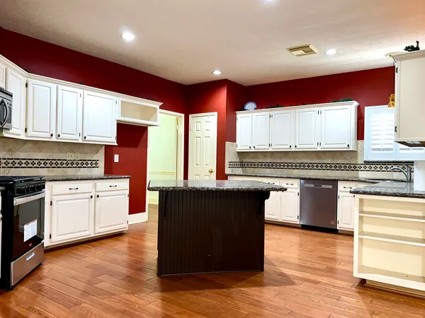 a kitchen with stainless steel appliances granite countertop a stove a sink and a microwave