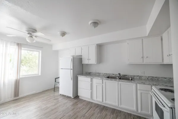 a kitchen with granite countertop white cabinets and white appliances