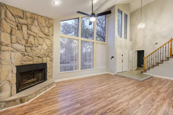 a view of an empty room with wooden floor fireplace and a window