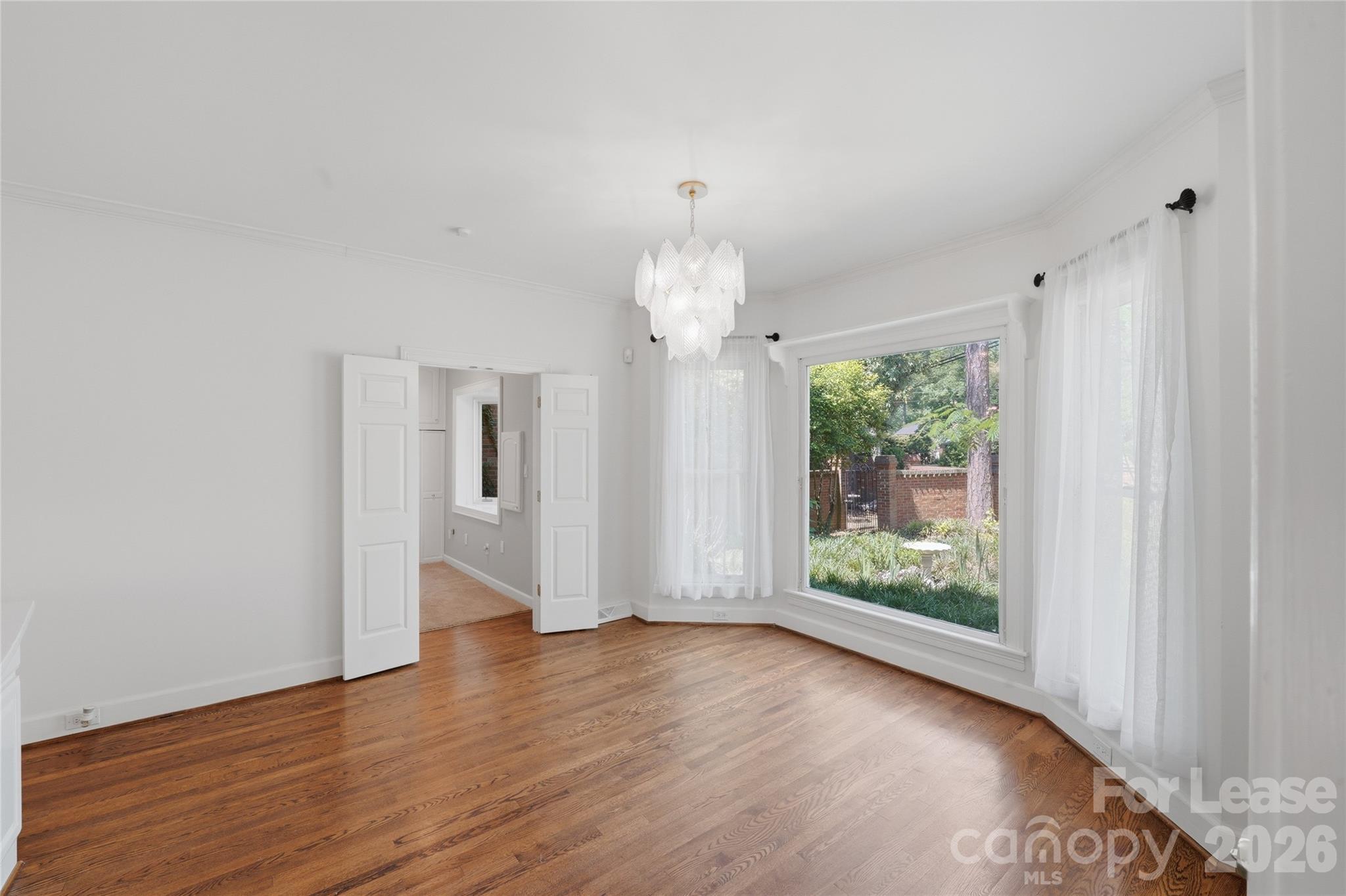5906 Sharon Hills Road Charlotte, NC 28210 - Photo 12 of 30 a view of an empty room with wooden floor and a window