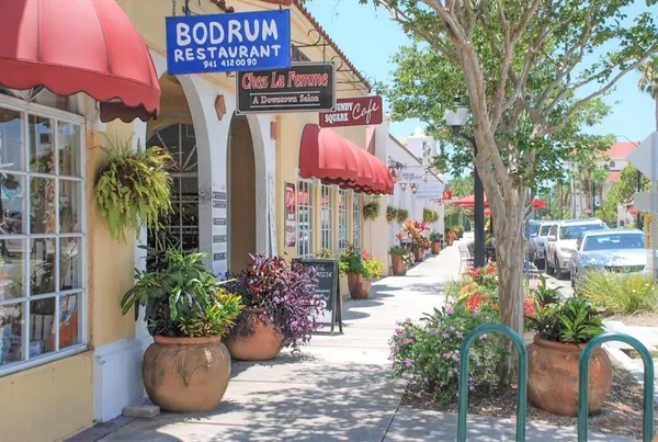 a front view of multi story residential apartment building with yard and sign board