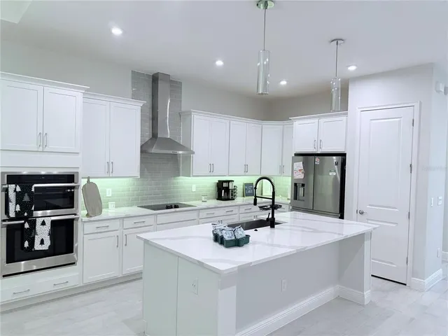 a kitchen with stainless steel appliances a sink a stove a microwave a center island and cabinets