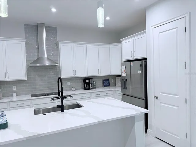 a kitchen with stainless steel appliances kitchen island sink refrigerator and cabinets