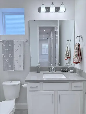 a bathroom with a granite countertop toilet sink and mirror