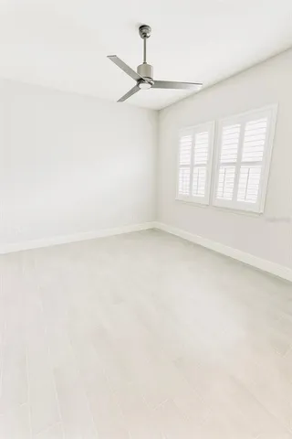 an empty room with windows and fan