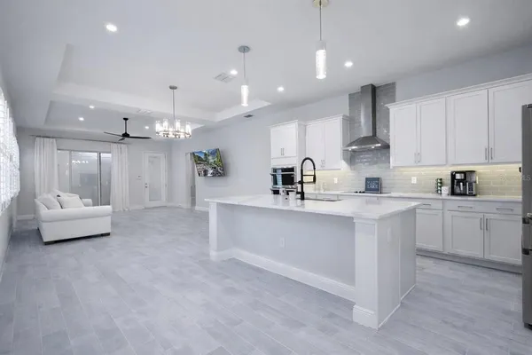 a large white kitchen with kitchen island a sink a stove a dining table and chairs