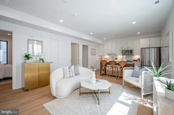 a living room with furniture kitchen view and a potted plant