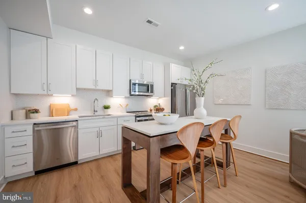 a kitchen with granite countertop white cabinets stove and chairs