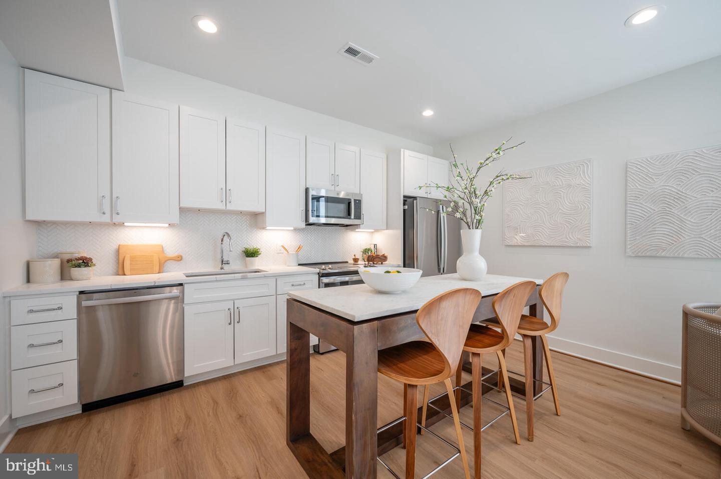 1228 Brentwood Road Northeast, Unit 1 Washington, DC 20018 - Photo 5 of 21 a kitchen with granite countertop white cabinets stove and chairs