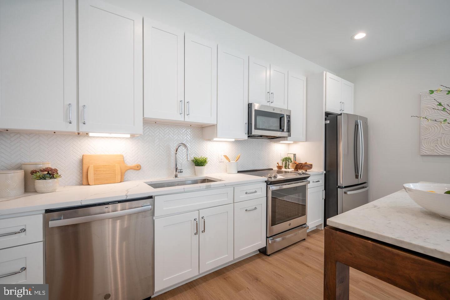 1228 Brentwood Road Northeast, Unit 1 Washington, DC 20018 - Photo 6 of 21 a kitchen with a sink white cabinets and stainless steel appliances
